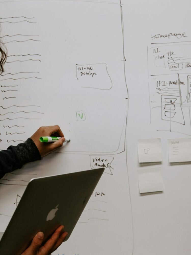 man wearing gray polo shirt beside dry-erase board