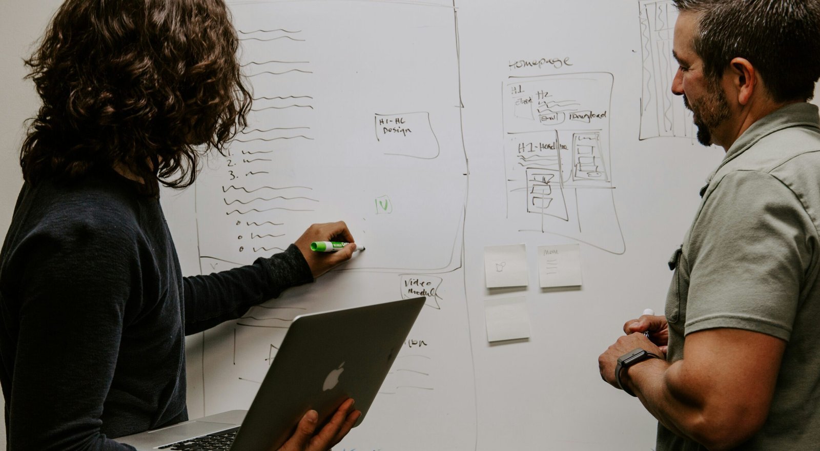 man wearing gray polo shirt beside dry-erase board